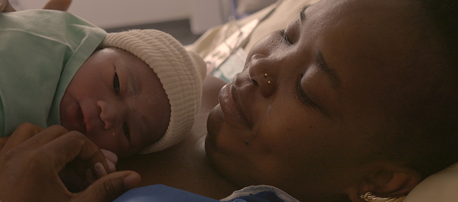 A mother of a newborn baby cradles the child against her chest. 