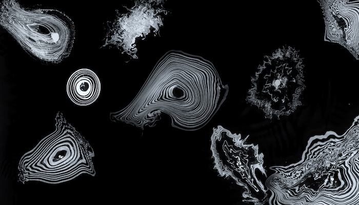 An assortment of abstract, ripple-effect-like patterns in white appear on a black background.