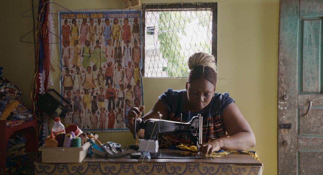 A woman sits and focuses on sewing with a vintage sewing machine.