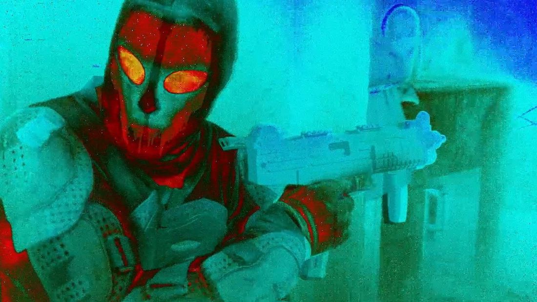 Infrared image of a man in full protective gear including a full face mask holding a gun.