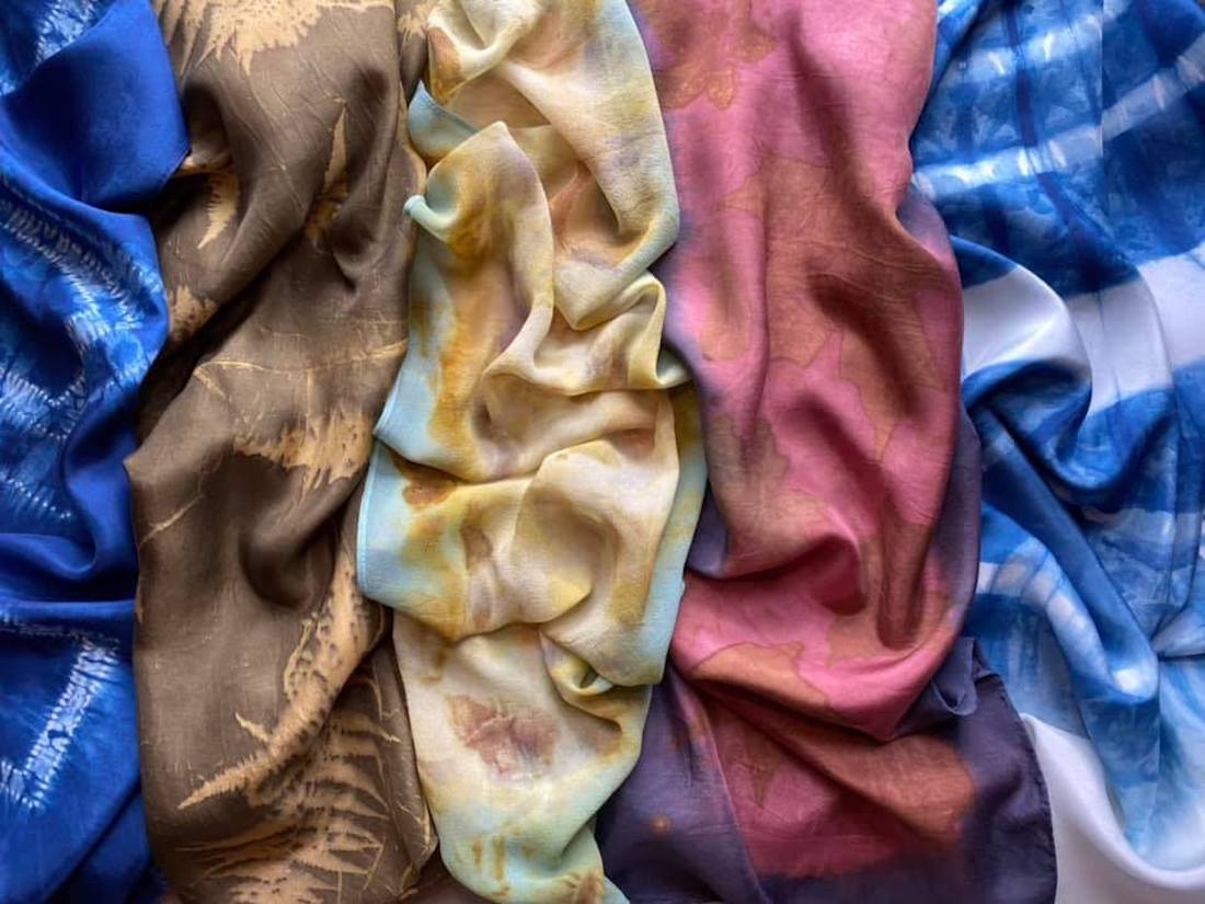 A vertical arrangement of five scarves dyed in a mix of vibrant colors.