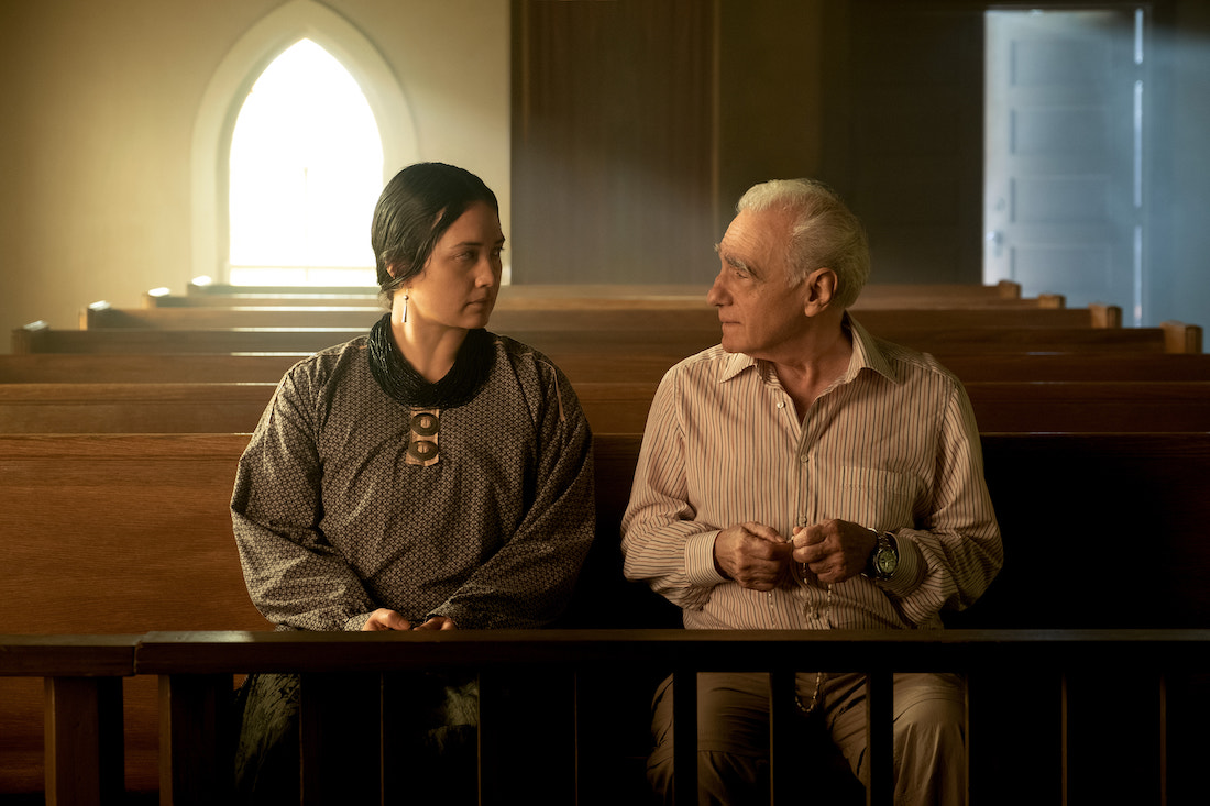 A woman and a man sit next to each other on a pew inside a church.