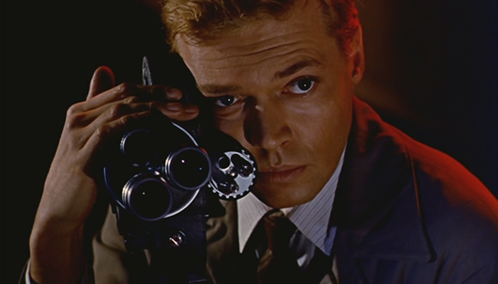 A closeup of a man clutching a movie camera to his face. 