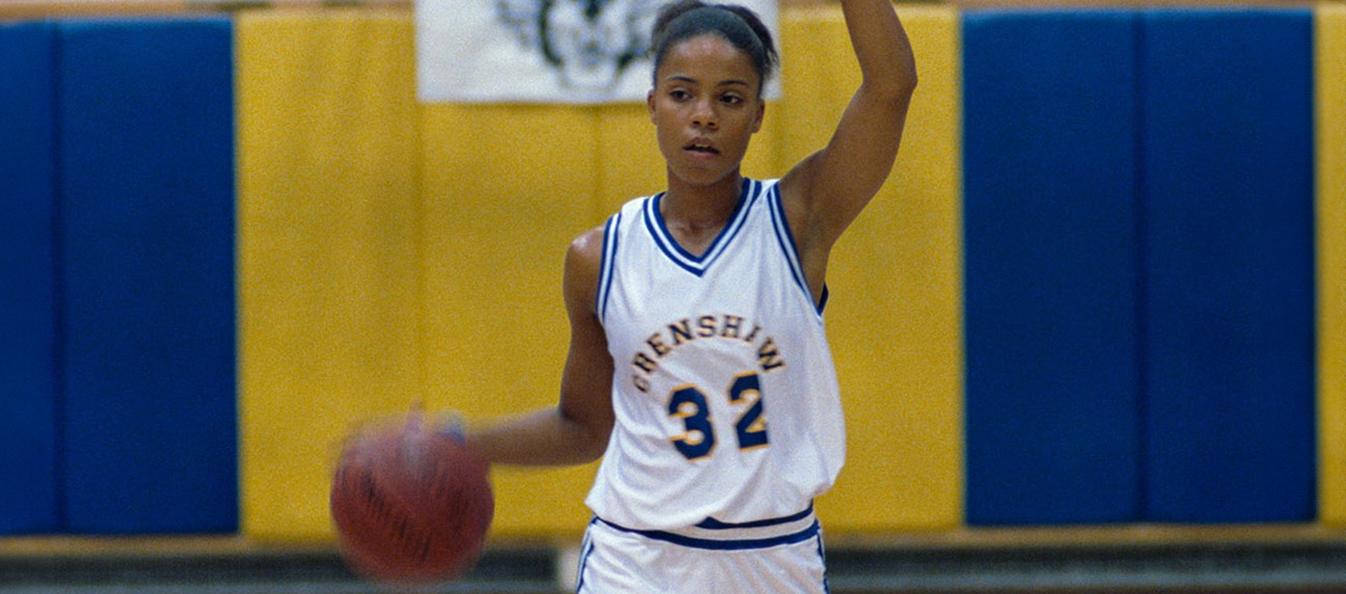 Still from Love & Basketball of a woman dribbling a basketball wearing a basketball uniform.