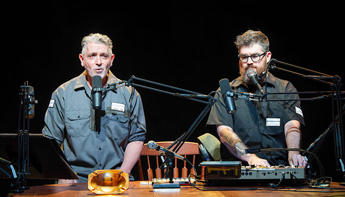 Ain Gordon and Josh Quillen performing Relics. The men are seated at a desk in front of microphones.