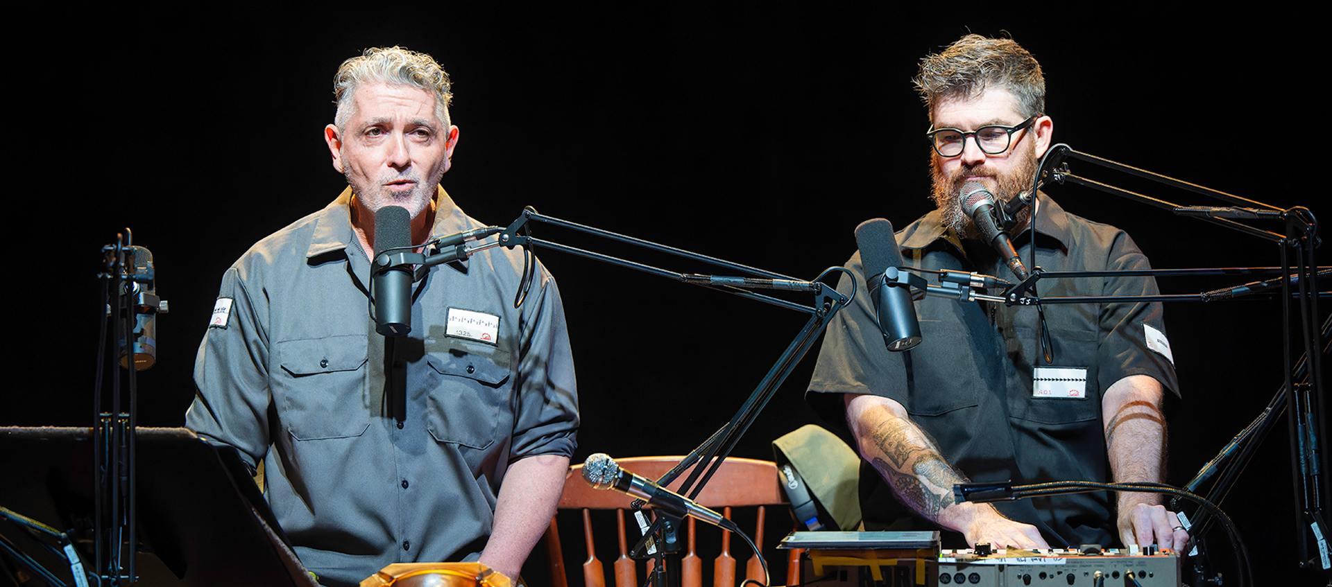 Ain Gordon and Josh Quillen performing Relics. The men are seated at a desk in front of microphones.