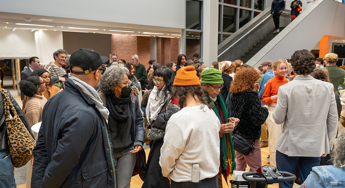 A large group of guests gather in the Wexner Center's lower lobby area.