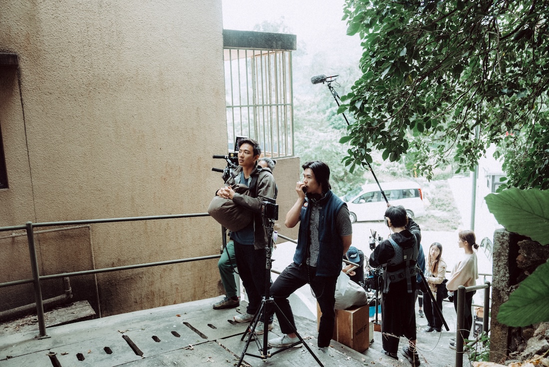 A camera crew gathers at an outdoor location and gets ready to shoot a scene.