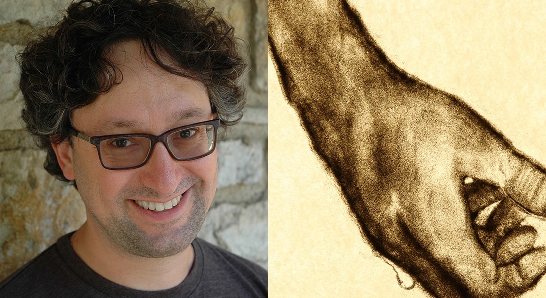 A photo of a smiling man with glasses next to an image of a human hand rendered in sand.