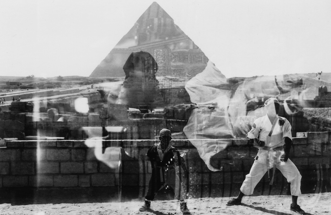 Double exposure photograph of a man and a boy on a bridge with the Egyptian Sphinx and a pyramid structure seen in the background.