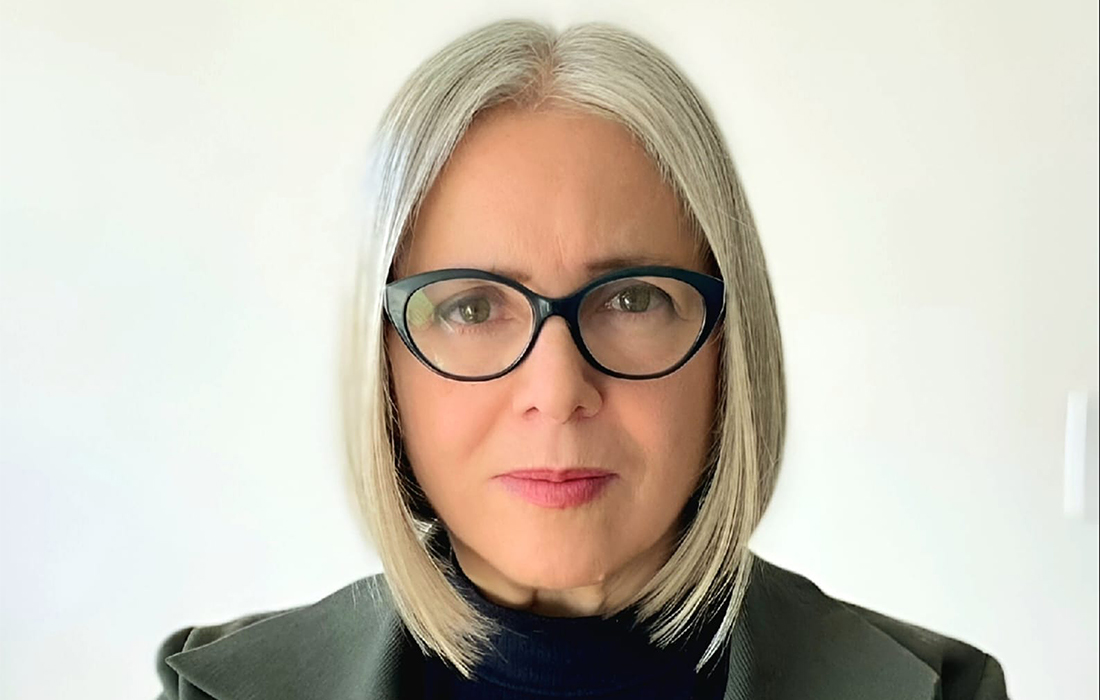 Head shot of a woman with glasses and shoulder-length white hair.