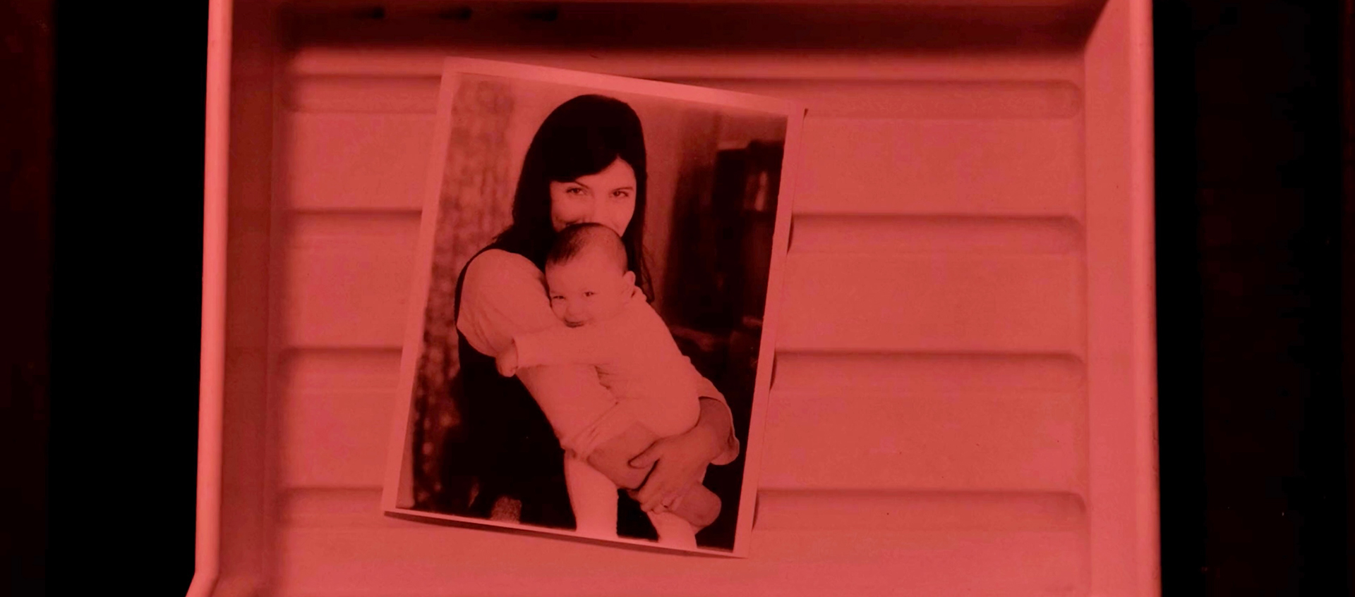 a photo of a woman holding a baby, the photo is in a tray.