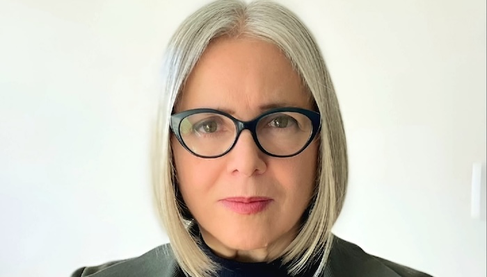 Head shot of a woman with glasses and white shoulder-length hair.