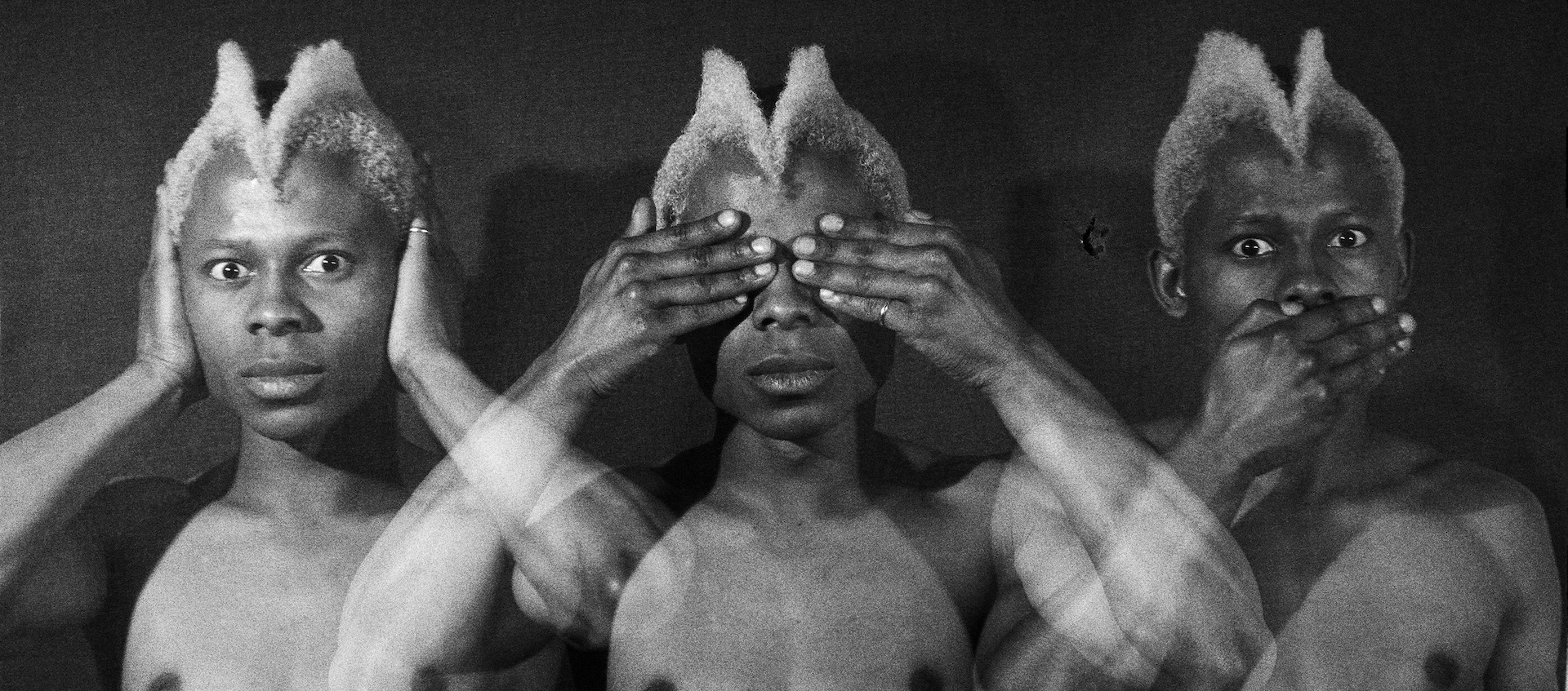 A triple exposure of a bare-chested Black man with a white mohawk hairstyle as he covers his ears, then his eyes, then his mouth.