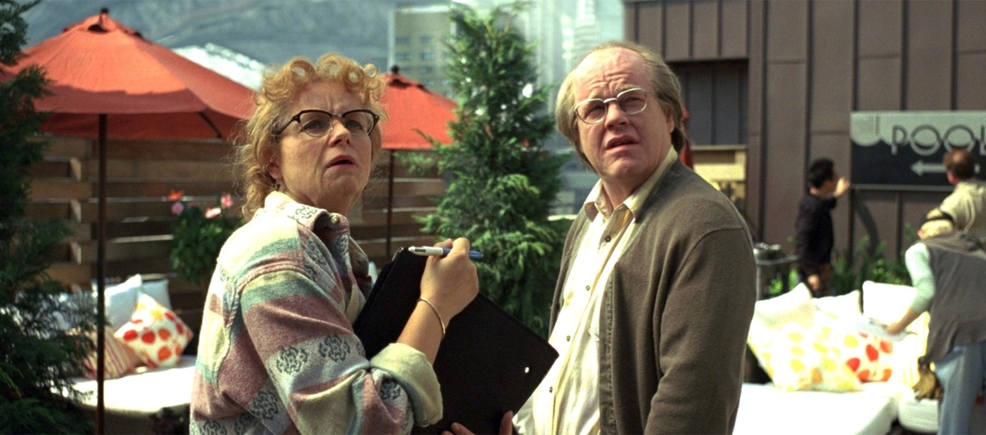 An older woman and man are standing in an outdoor patio area looking up at something.