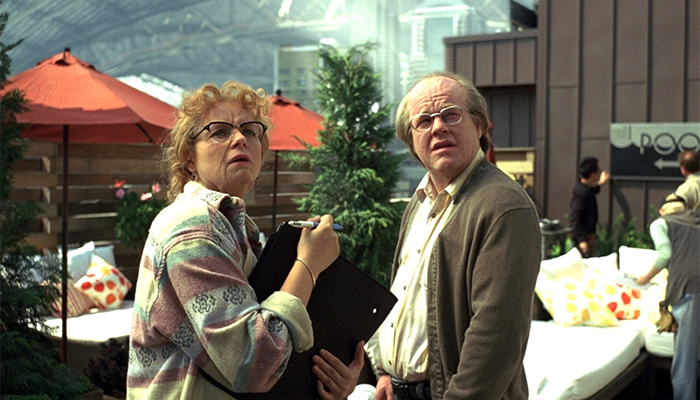 An older woman and man are standing in an outdoor patio area looking up at something.