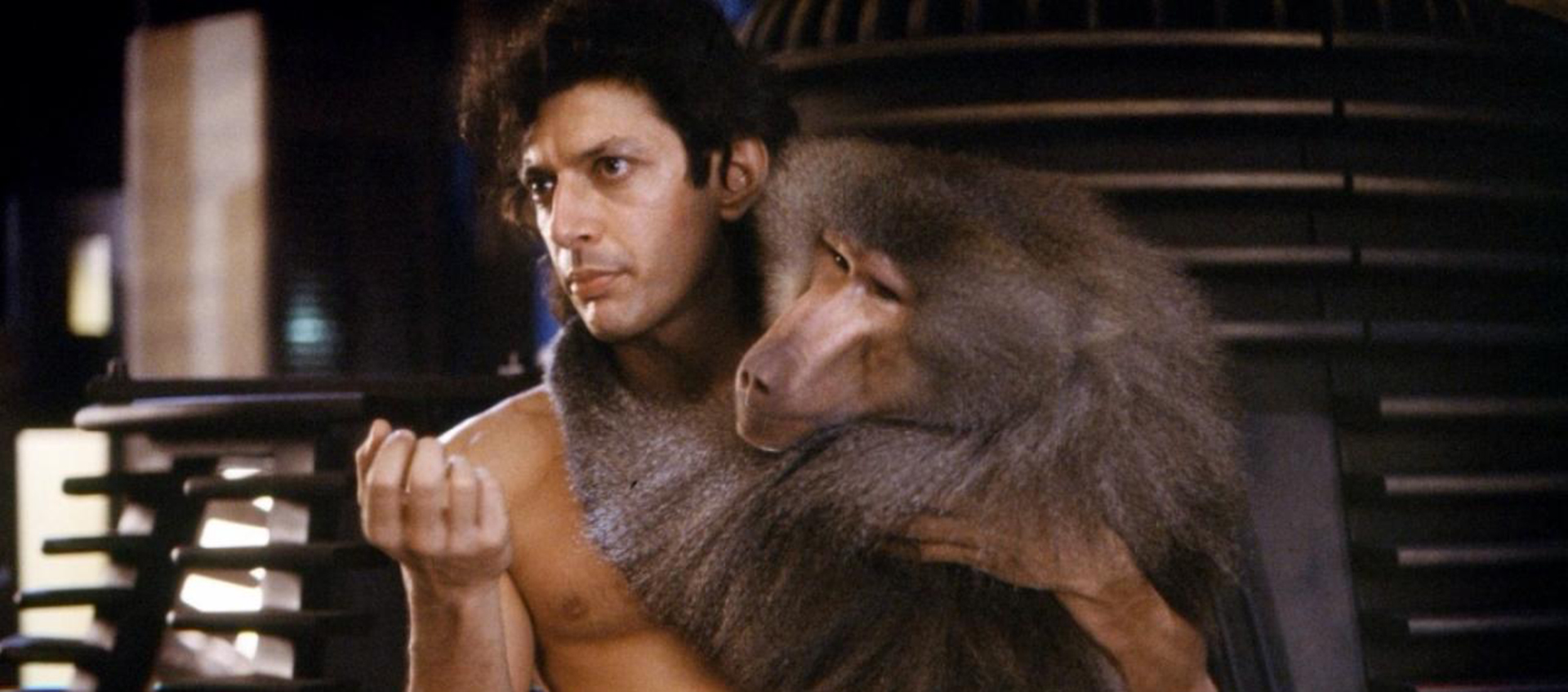 Actor Jeff Goldblum is shirtless and holding a monkey in his arms.