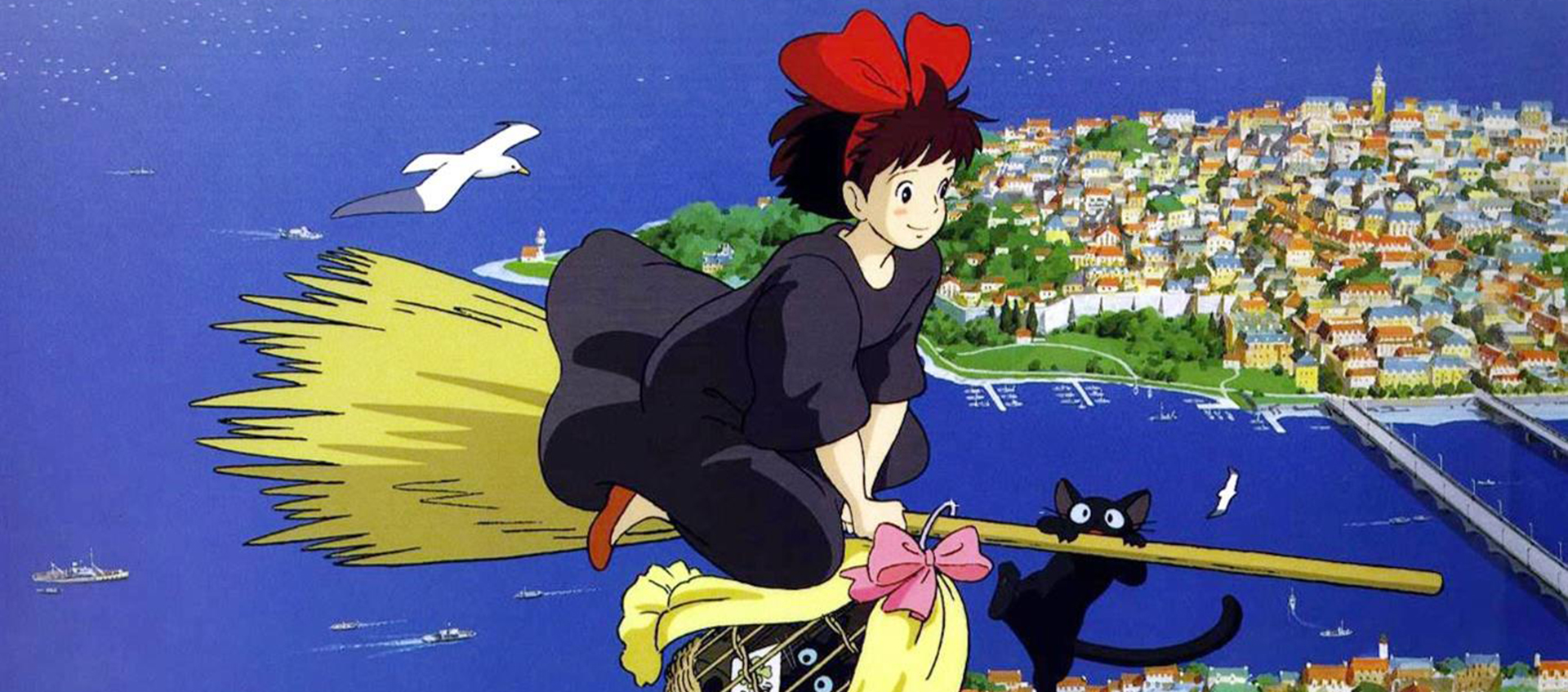 An animated girl with a red bow and a black cat ride a broomstick over a coastal city and harbor with boats and seagulls below.