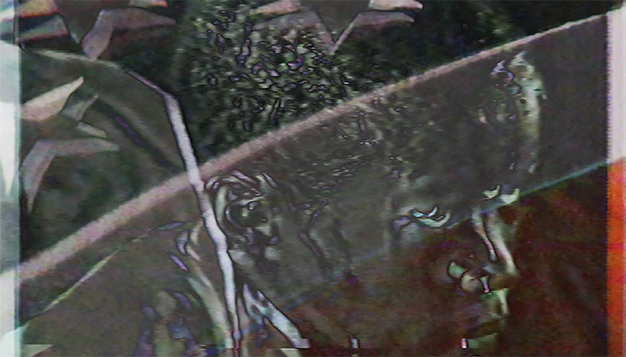 A distorted, glitch-style image of a person’s face and upper body with diagonal lines and visual noise effects.