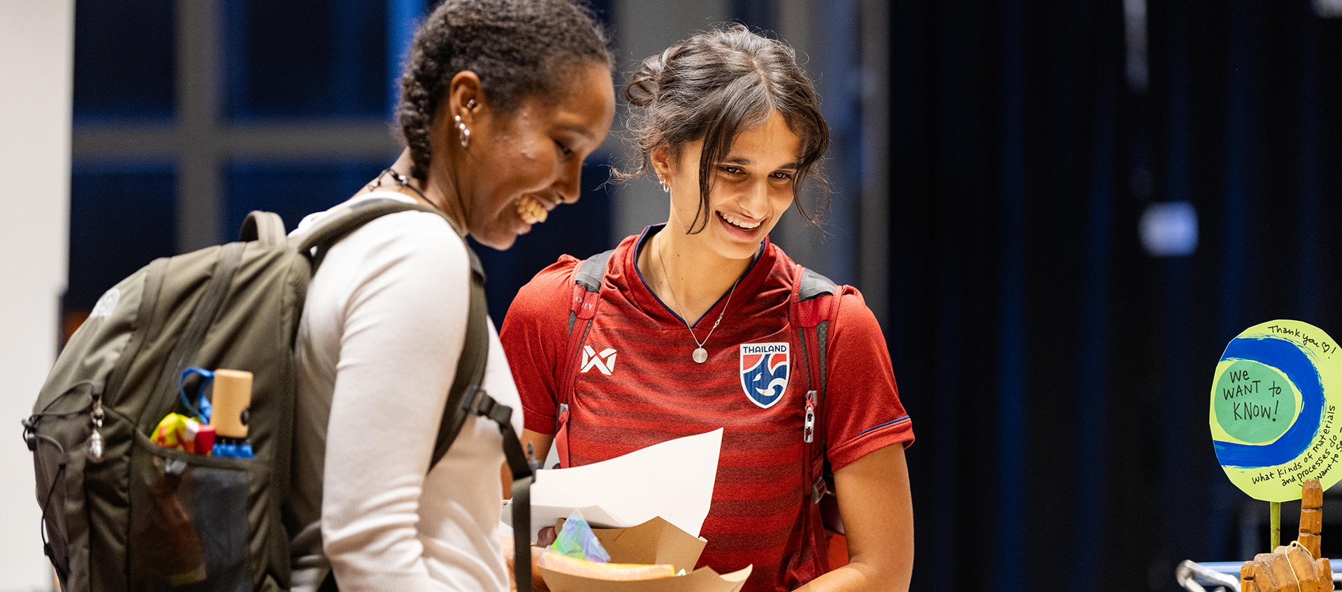 Two students stand smiling in the Wexner Center.