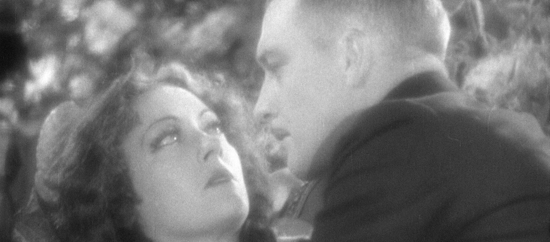 Black-and-white still featuring Gloria Swanson and Walter Byron. Byron leans in toward Swanson, and she backs away.