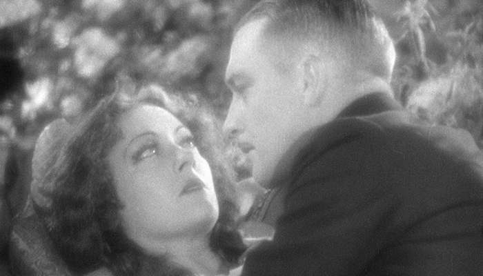 Black-and-white still featuring Gloria Swanson and Walter Byron. Byron leans in toward Swanson, and she backs away.