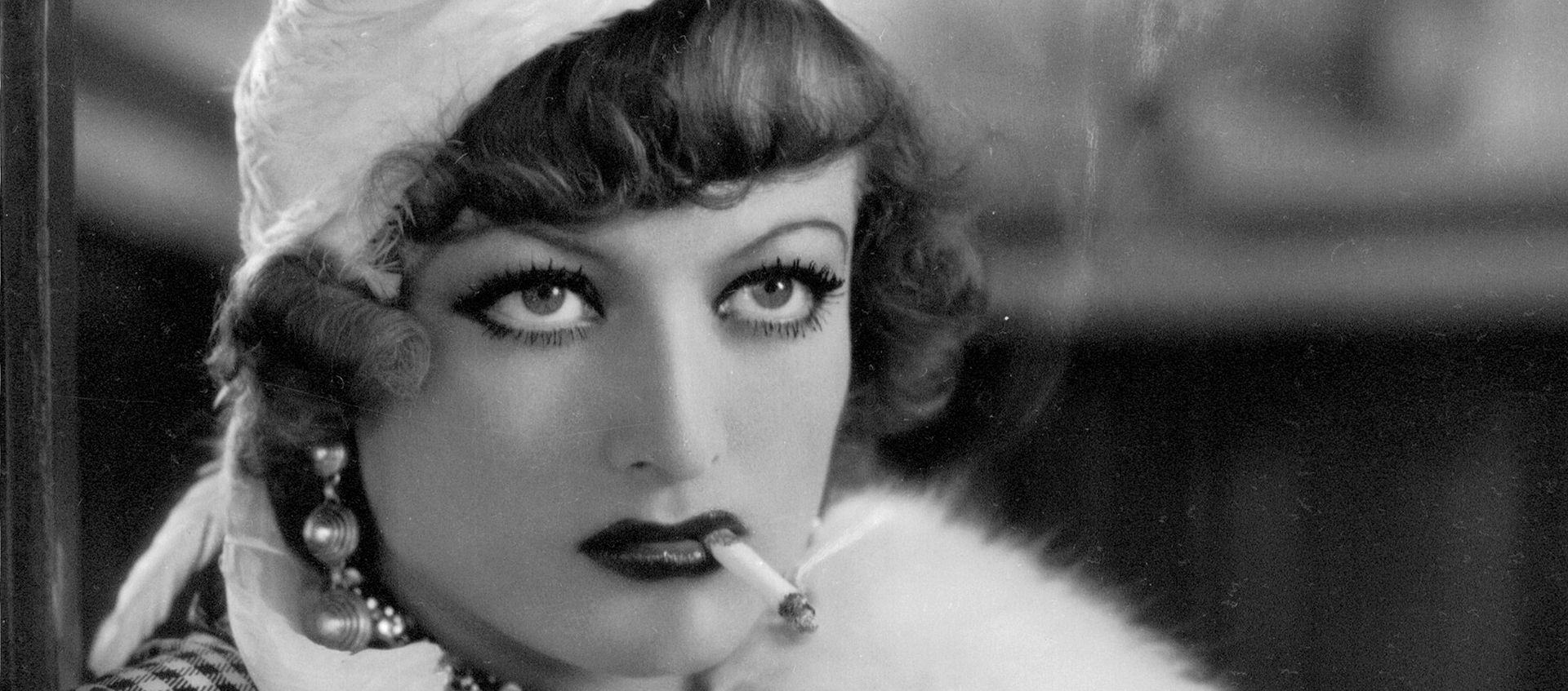 Closeup of Joan Crawford as Sadie. She holds cigarette in between her lips.