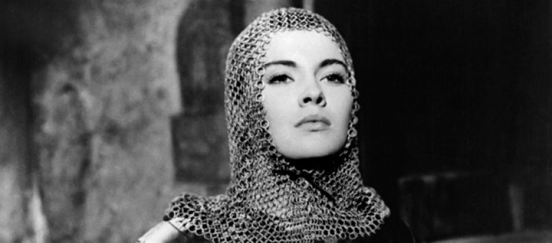 Black-and-white still of a woman wearing a chainmail headpiece.