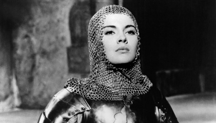 Black-and-white still of a woman wearing a chainmail headpiece.