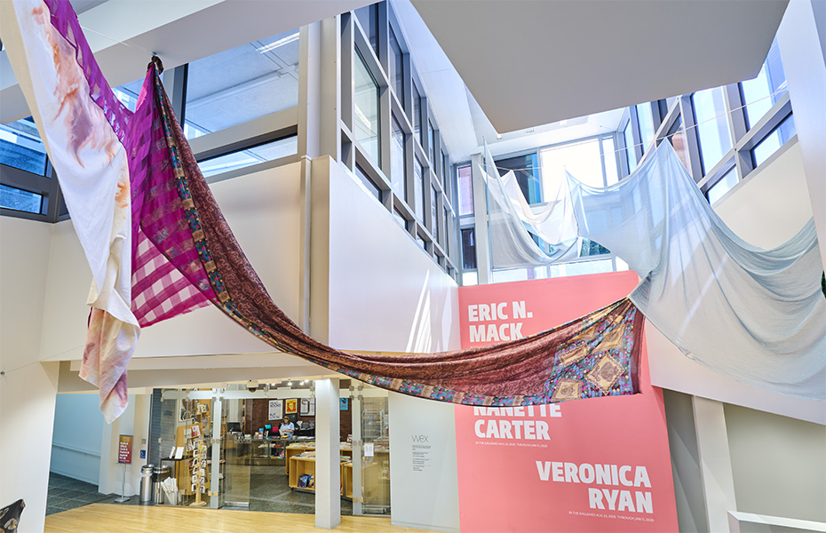 A colorful installation of fabrics hanging from the ceiling of the Wexner Center lobby.