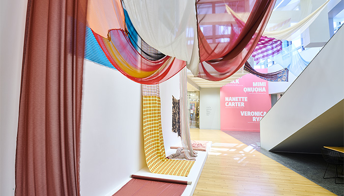 A colorful installation of fabrics hanging from the ceiling and walls of the Wexner Center lobby.