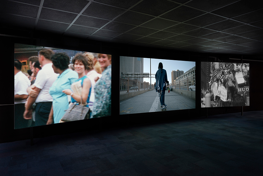 Three large screens project images in a dark room.
