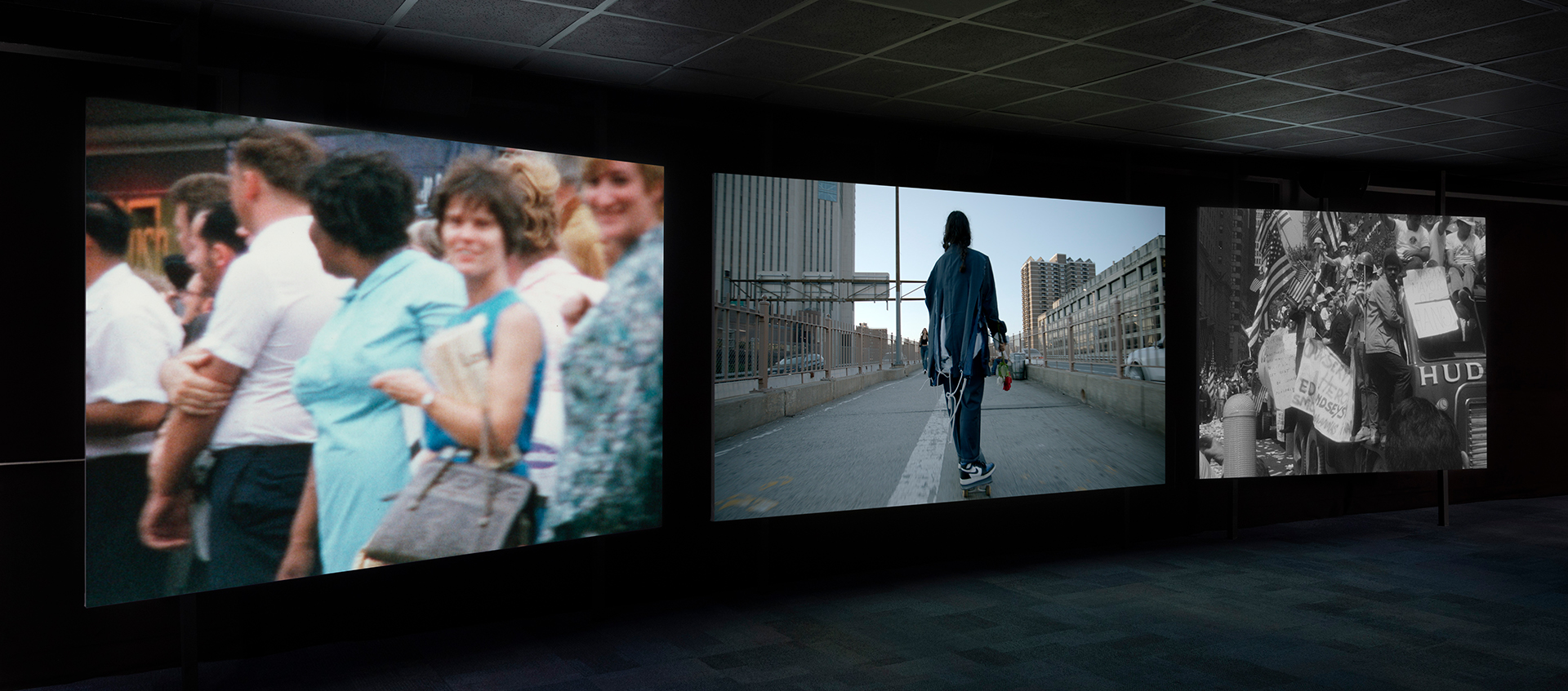 Three large screens project images in a dark room.