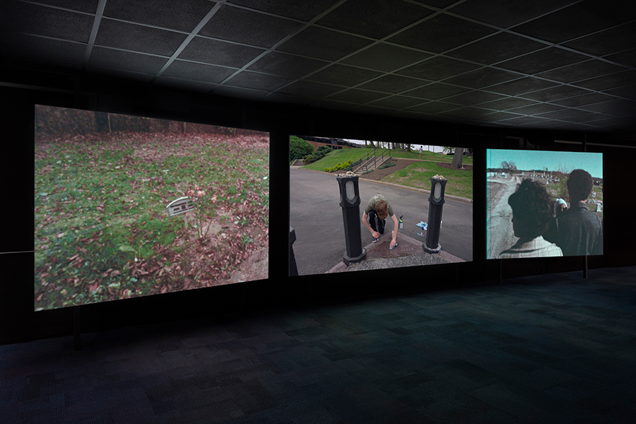 Three large screens project images in a dark room.