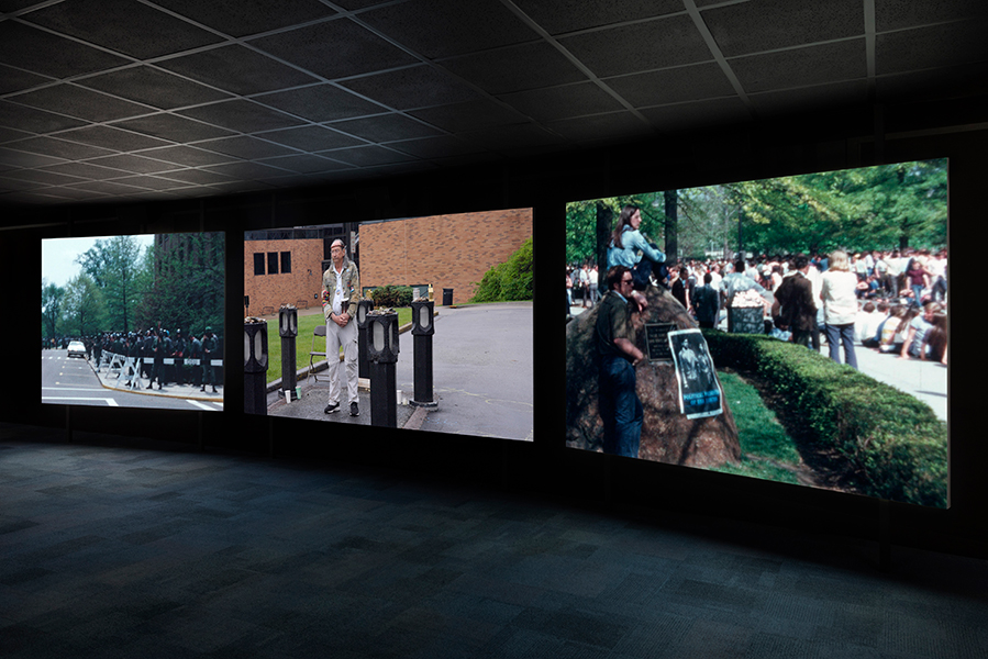 Three large screens project images in a dark room.