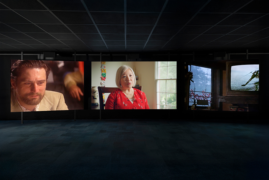 Three large screens project images in a dark room.