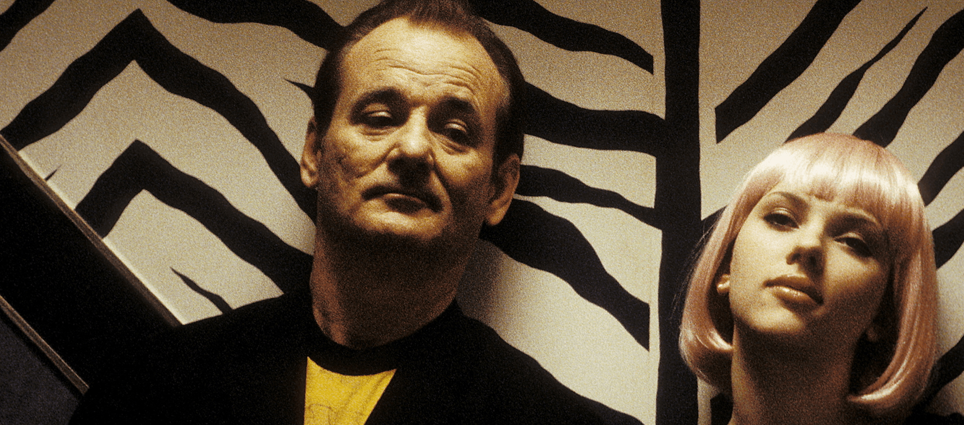 Bill Murray and Scarlett Johansson stand in front of a tiger striped wall.