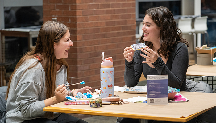 Two young adults sit in Heirloom Café with cookies they decorated.