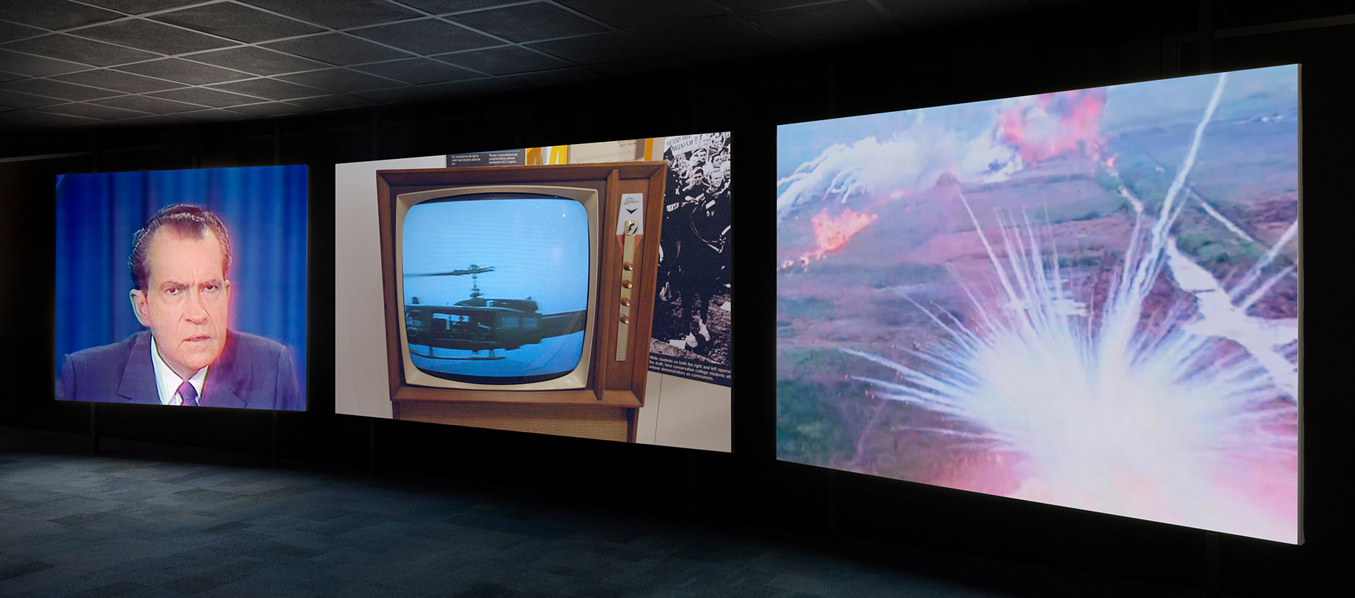 Three large screens project images in a dark room.