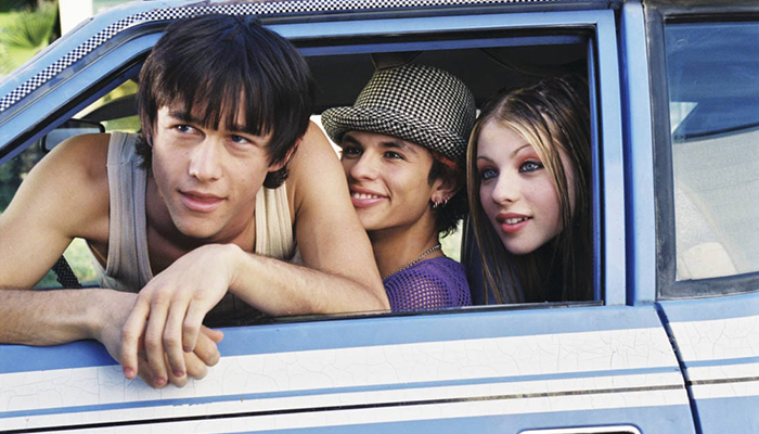 Three young people lean out of a car window.