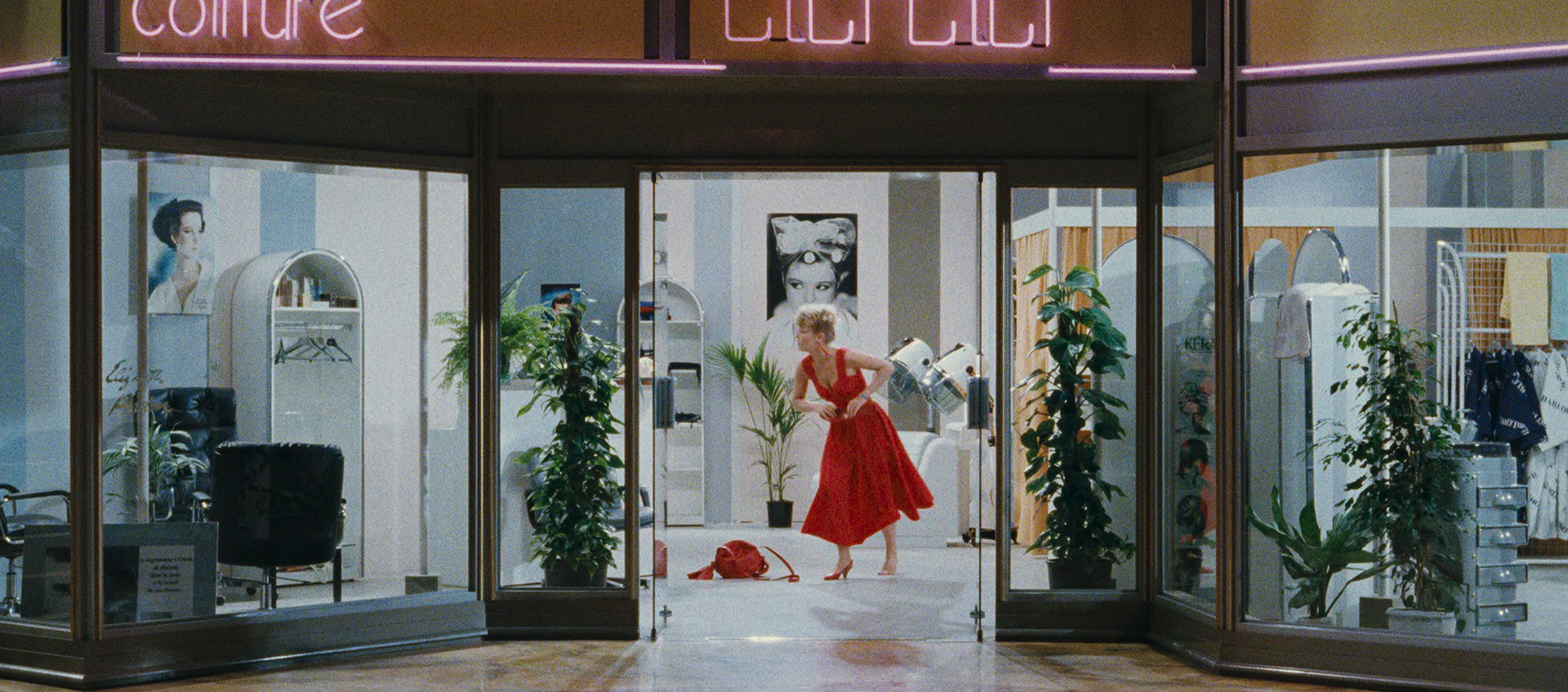 A mall storefront with woman in a red dress standing in the doorway.