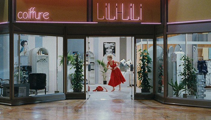 A mall storefront with woman in a red dress standing in the doorway.