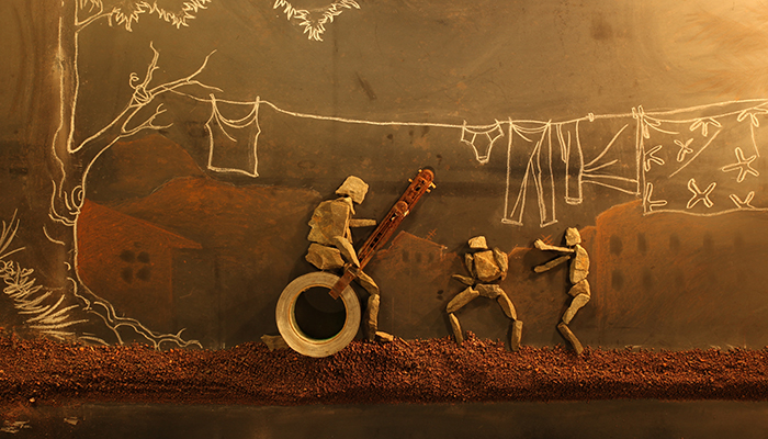 Rock figures are positioned on a blackboard with a chalk drawing of clothes hanging on a line attached to a tree and houses in the background.