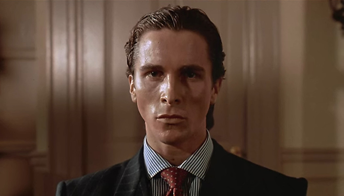 A closeup of Christian Bale with slicked back hair and a suit.