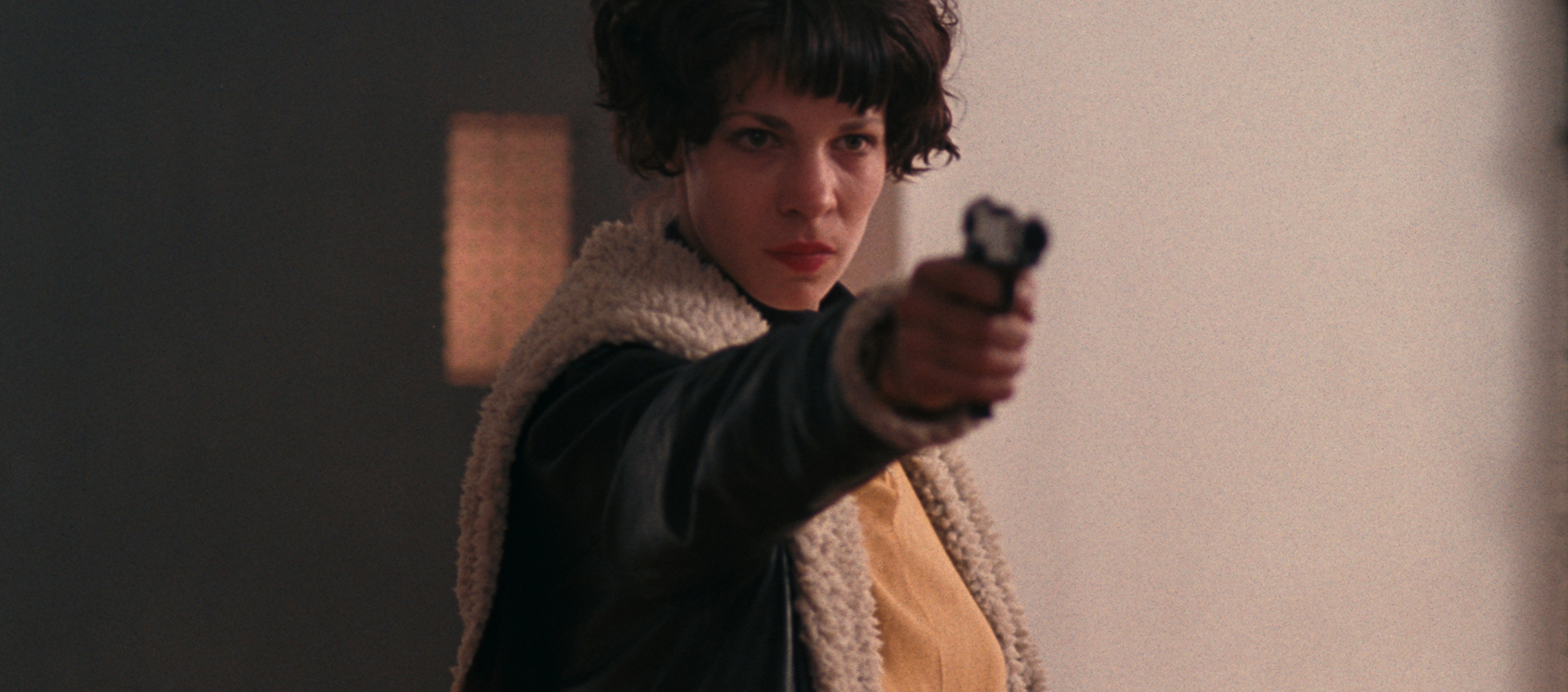 A woman stands with her arm outstretched holding a handgun.