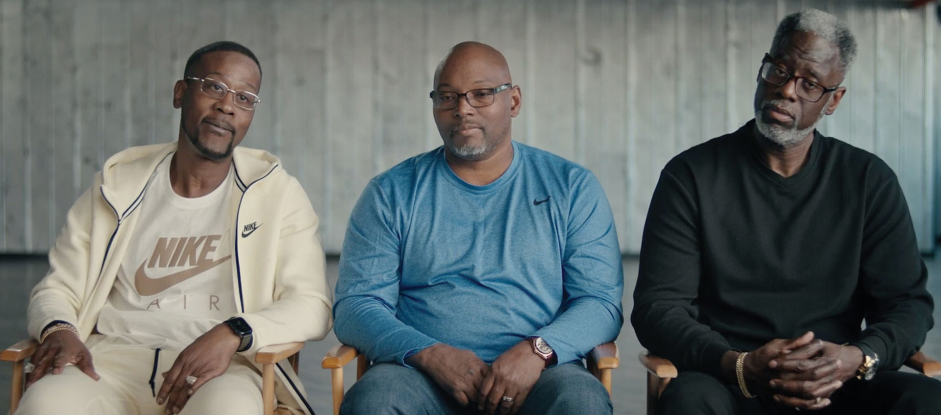 Three men sit in chairs next to each other 