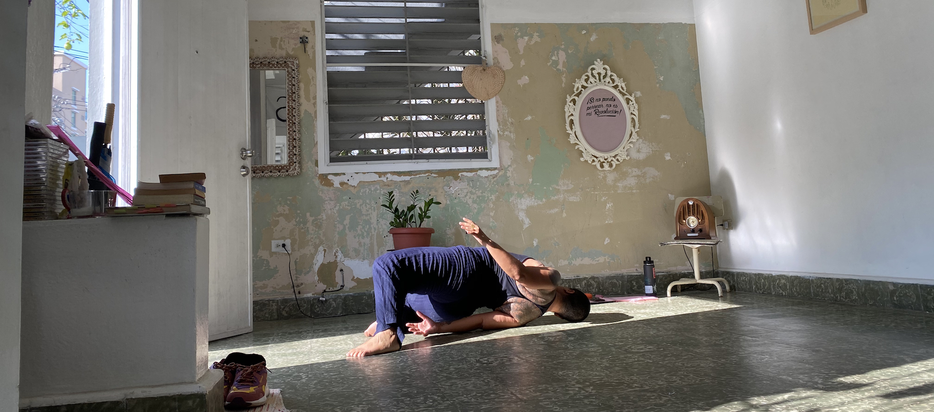 Movement artist Awilda Rodriguez Lora lies on the floor of her home La Rosario in Puerto Rico, her knees bent and her back arched with her left hip lifted off the floor so she's facing away from the camera